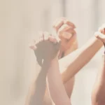 Mehrere Paar Hände unterschiedlicher Hautfarben greifen sich gegenseitig fest