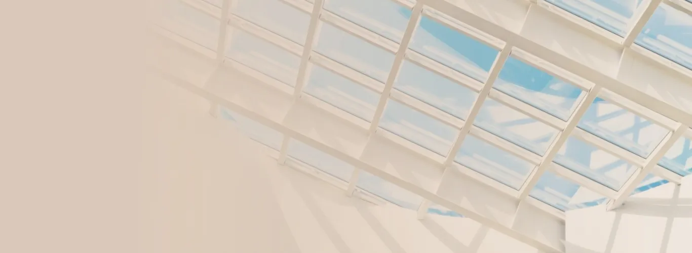 Blick durch ein Glasdach mit weißem Rahmen auf blauen Himmel mit Wolken
